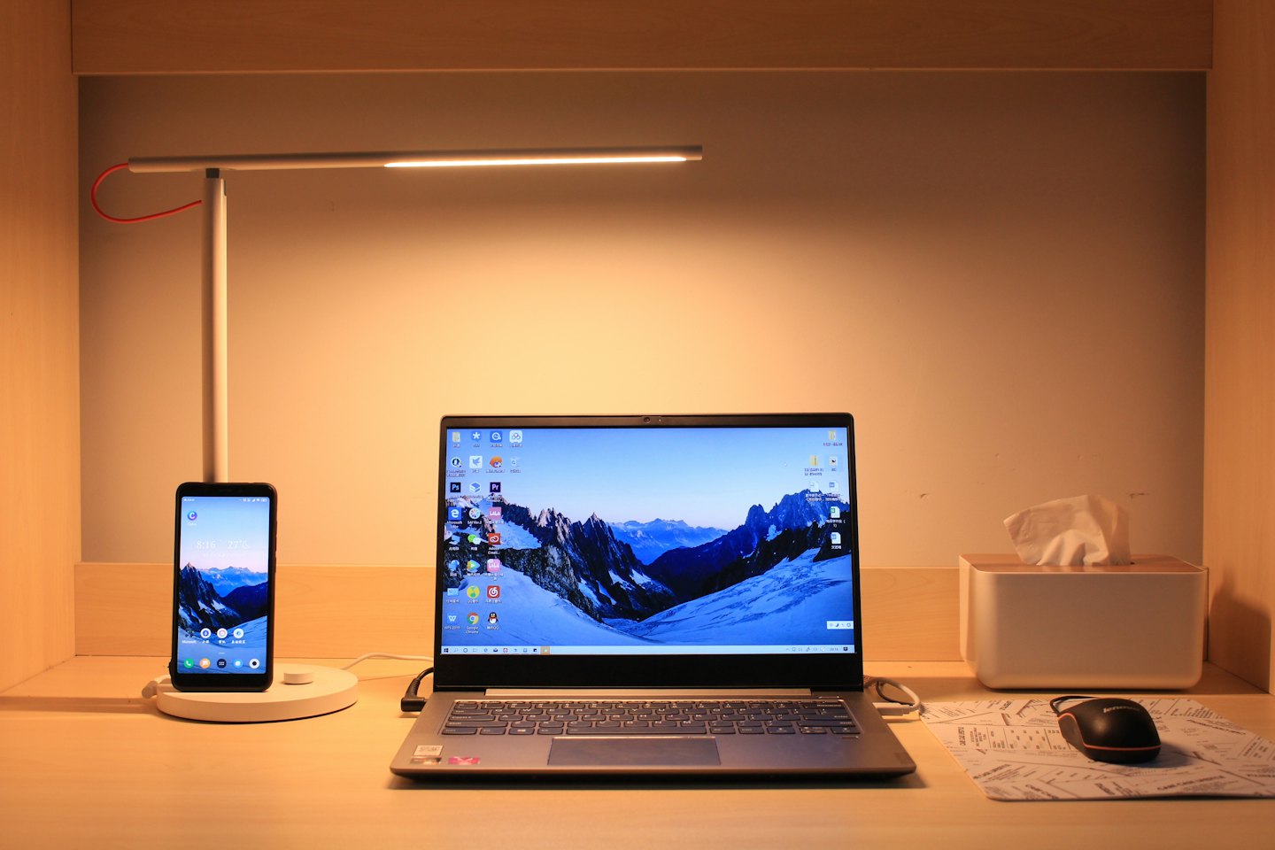 Laptop en smartphone die opladen op een houten bureau.
